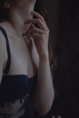 A girl with black hair in black underwear sits on a chair by the window