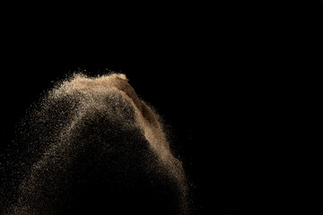 Golden colored sand splash against dark background. 