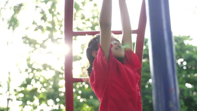 Little Asian girl playing on monkey bars at playground