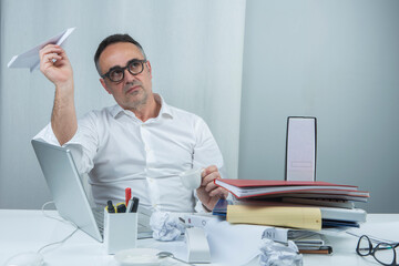Manager cinquantenne vestito in camicia bianca è seduto nella sua postazione di lavoro mentre...