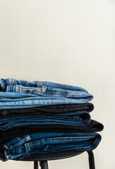 a stack of blue jeans on a chair    
