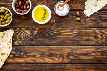 Top view of olives, olive oil, bread on wooden table top view copy space