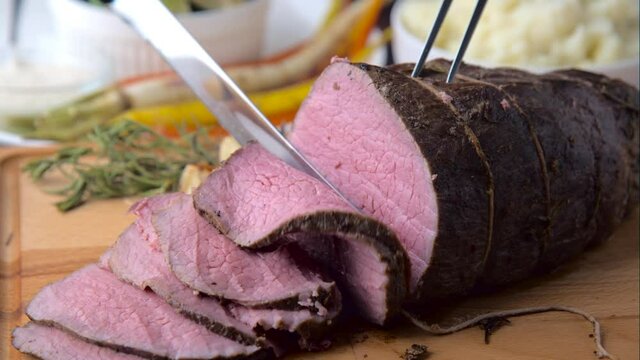 carving roast beef with knife and fork
