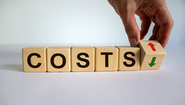 Hand is turning a cube and changes the direction of an arrow symbolizing that the costs is going down or vice versa. Beautiful white background, copy space. Business concept.