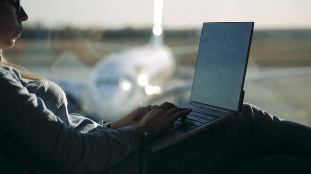 A woman is browsing her computer while expecting her flight