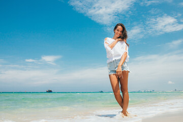 A young beautiful girl walks and enjoys on a tropical sea beach. Seascape in the background. The concept of a summer holiday at sea