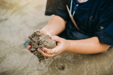 Kids playing in the clay muddy puddle field. This activity is good for sensory experience and learning by touch their fingers through clay and enjoying its texture. - obrazy, fototapety, plakaty