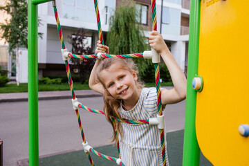 Portrait of girl climbing at the playing rope at the playground.