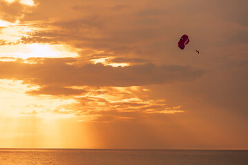 Landscape of orange sunset with parachutist. Naval adventure