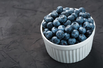 Blueberries in a white Cup on a black textured background.