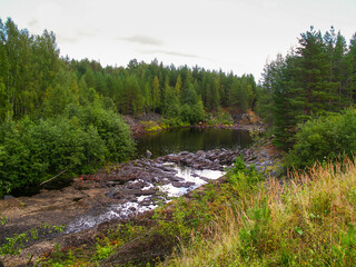 Landscape. Lake in the forest with stony rocks.