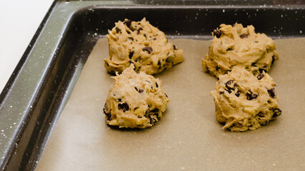 Chocolate Chip Cookies recipe. Placing cookie batter on a baking sheet, close up on white background,