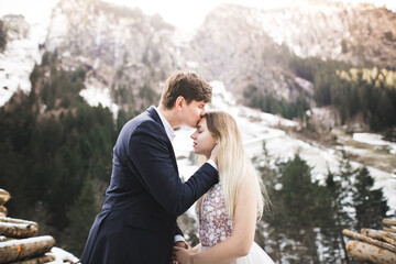Young happy couple kissing, mountains landscape in snow on the background