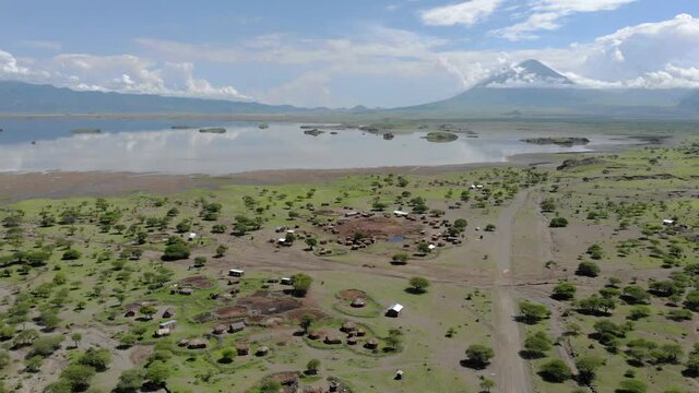 Aerial Flyby View on the Maasai village in on the coast of Natron Lake front of the Ol Doinyo Lengai, Mountain of God in the Maasai language, Engare Sero village in Arusha Region i the Northern