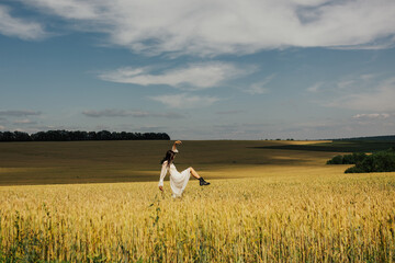 Cheerful young woman on the field at summer sunny day. Pretty girl having fun in a field and smiles...