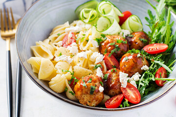 Italian pasta. Conchiglie with meatballs, feta cheese and salad on light background. Dinner. Slow food concept
