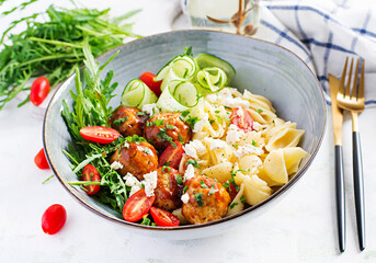 Italian pasta. Conchiglie with meatballs, feta cheese and salad on light background. Dinner. Slow food concept