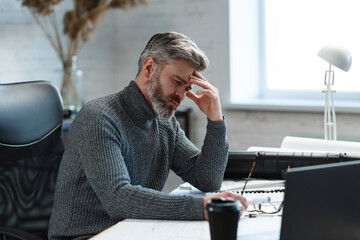 Tired architect working overtime in office. Stressed businessman have financial problems and searching ideas to overcome financial crisis. Entrepreneur in bankruptcy. Burnout and overwork concept.