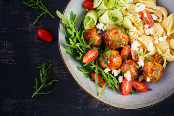 Italian pasta. Conchiglie with meatballs, feta cheese and salad on dark background. Dinner. Top view, overhead. Slow food concept