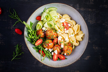 Italian pasta. Conchiglie with meatballs, feta cheese and salad on dark background. Dinner. Top view, overhead. Slow food concept