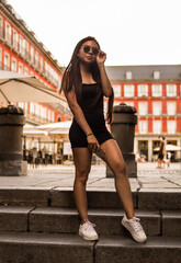 Young hispanic woman posing on a summer day while strolling through a square