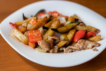 Pan-Asian dish: pork with eggplant, carrots, peppers, potatoes and onions in a sweet and sour sauce. Street cafe in the city.