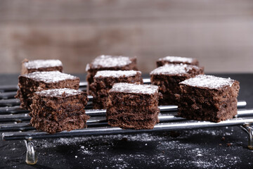 square pieces of chocolate and sugar glass cake on a steel grid with a brown background