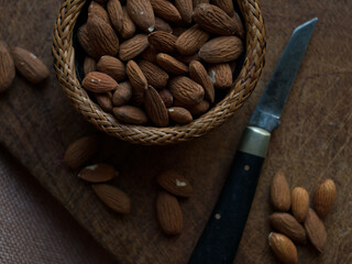 Rustic simple almonds on dark wooden board and farm kitchen table with vintage pocket knife.