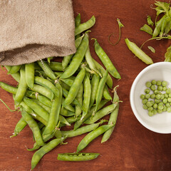 green peas, pods and peas in a canvas bag on a wooden background. flatlay.