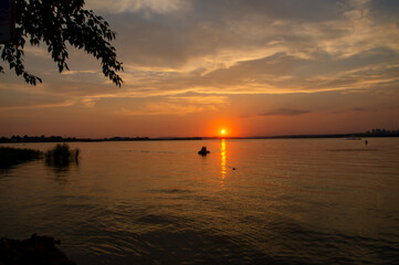 Fototapeta na wymiar The sun sets over the city pond. Pond at sunset with sun glare