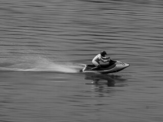 RC controlled jet ski model on lake black and white.