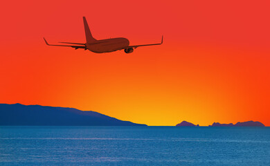Airplane flying above tropical sea at sunset