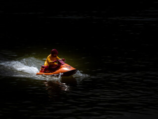 RC controlled jet ski model on lake. Black background
