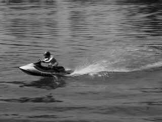 RC controlled jet ski model on lake black and white.