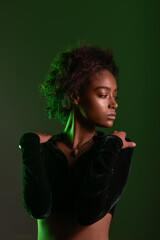 Portrait Of African American Woman Holding On Shoulders. Studio dark green light