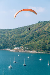 Paragliding in the sky. Paragliding flying over the sea with blue water on a sunny day. Aerial view