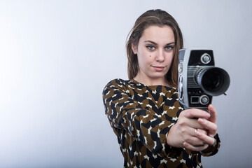 Bella ragazza bionda, vestita casual utilizza la sua vecchia cinepresa vintage, puntandola in...