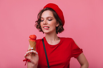 Inspired female model with wavy hairstyle looking at ice cream with smile. Sensual french girl in...