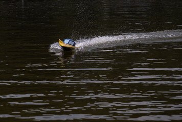 RC controlled speedboat model on lake. Active summer vacation for school child.