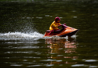 RC controlled jet ski model on lake.