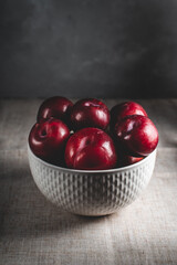 fresh ripe fruit plums lie in a light bowl on a linen tablecloth with dark lighting
