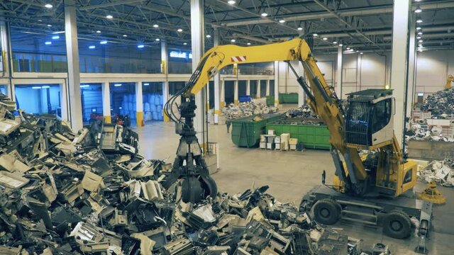 Working machine sorts gargabe at a recycling center. Trash, e-waste, electronic garbage recycling factory.