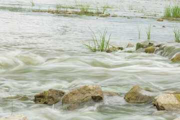 The flow of the river in the summer forest. Stones washed by water. Reflection on the water. water movement for a long exposure.