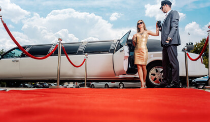 Driver helping VIP woman or star out of limo on red carpet