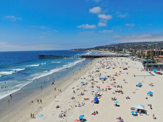 Aerial view of people at the beach near the pier with during blue summer day. Pacific Beach in San Diego, California  - obrazy, fototapety, plakaty