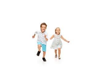 Happy children, little and emotional caucasian boy and girl jumping and running isolated on white background. Look happy, cheerful, sincere. Copyspace for ad. Childhood, education, happiness concept.