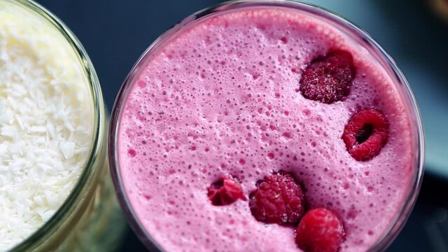 Footage of raspberry smoothie drink with berries on top shot from above on table in cafe.Video clip of delicious detox beverage with milk & berries for breakfast meal