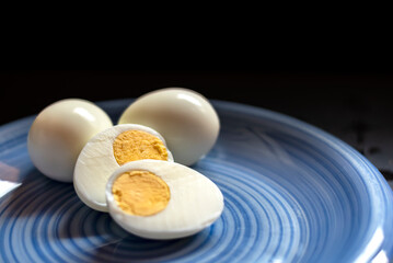 Hard boiled eggs on blue plate and dark background