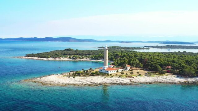 Drone flying around monumental lighthouse of Veli Rat on the island of Dugi Otok, Croatia, beautiful Adriatic seascape and rocks