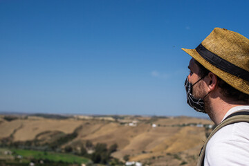 Photo of a young and attractive man wearing a face mask enjoying the views doing tourism during coronavirus outbreak. Social distance and isolation	